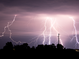 A dark night's sky is filled with bright white streaks of lightning from an electrical storm 