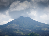 A volcano emits dark grey smoke and ash clouds into the sky 